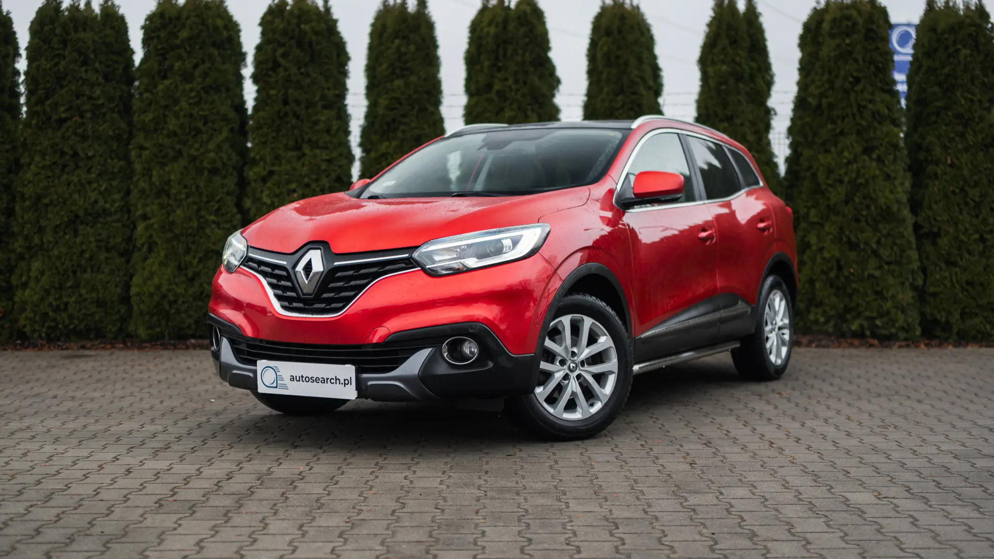Zdjęcie lewej sylwetki pojazdu Renault Kadjar z 2015 roku w wersji Intense w kolorze Flame REd